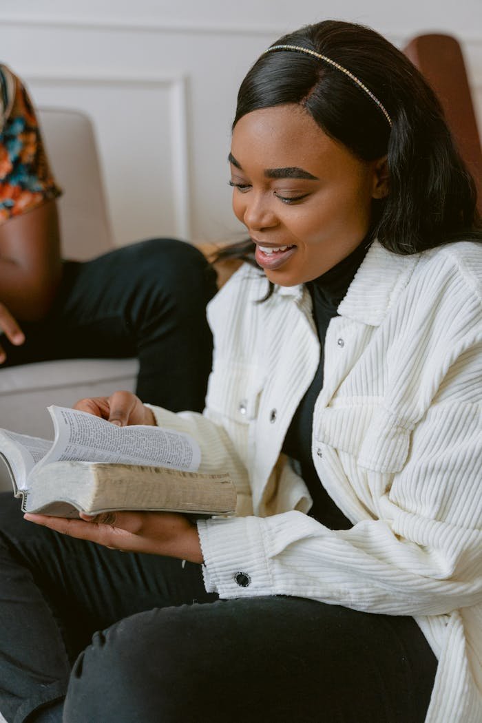 Smiling young woman engaged in reading a bible indoors. Peaceful and reflective moment.